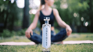 bottle of amethyst nonalcoholic spirit with a woman sitting cross legged in the background