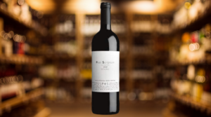 a bottle of Prats & Symington Post Scriptum Red Blend on a background image of a blurry celler