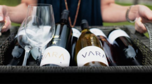 woman holding a basket of vara wines and wine glasses